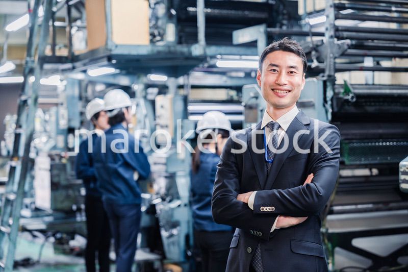 工場で腕を組むホワイトカラーの男性