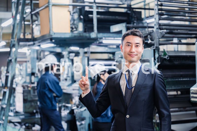 工場で指を指すビジネスマン