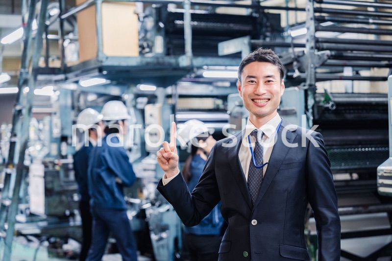 工場で指を指すビジネスマン