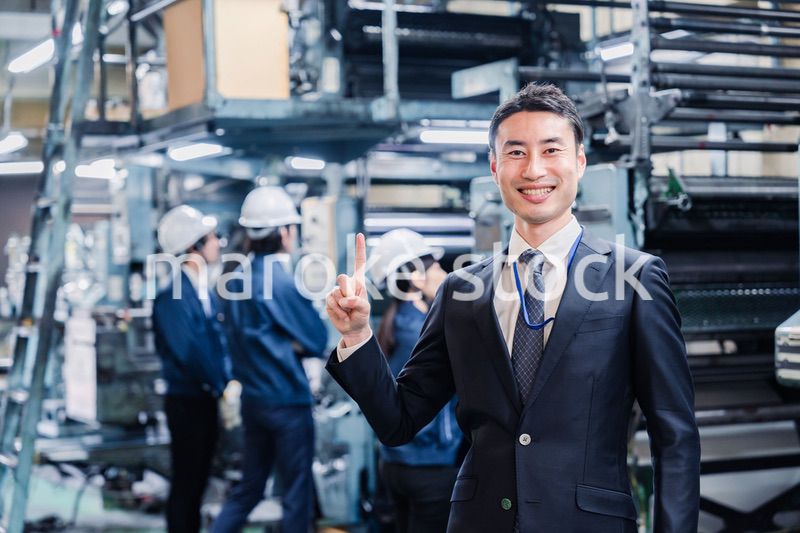 工場で指を指すビジネスマン