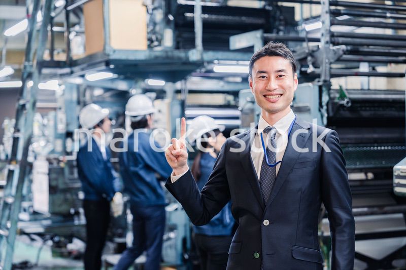 工場で指を指すビジネスマン