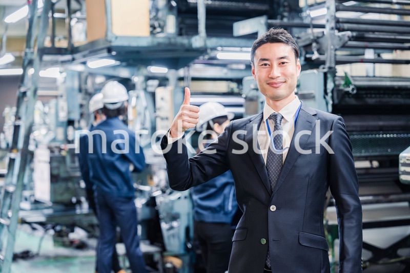 工場でOKサインをするビジネスマン