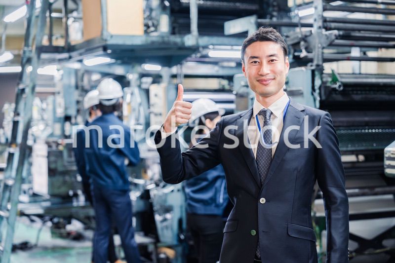工場でOKサインをするビジネスマン