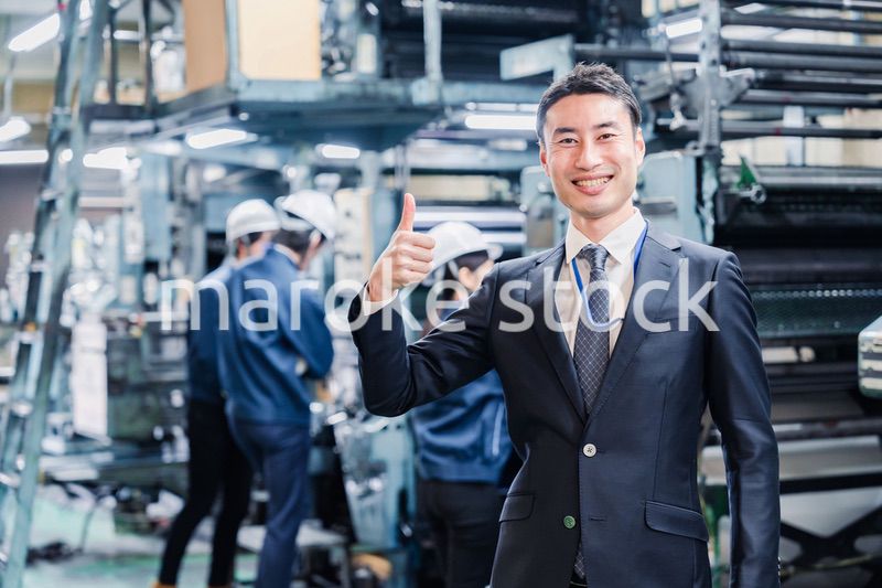 工場でOKサインをするビジネスマン