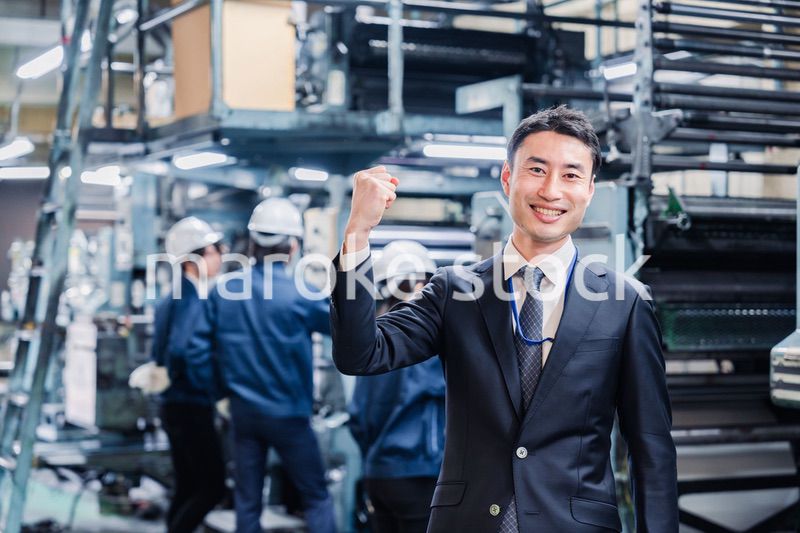 工場でガッツポーズをするビジネスマン