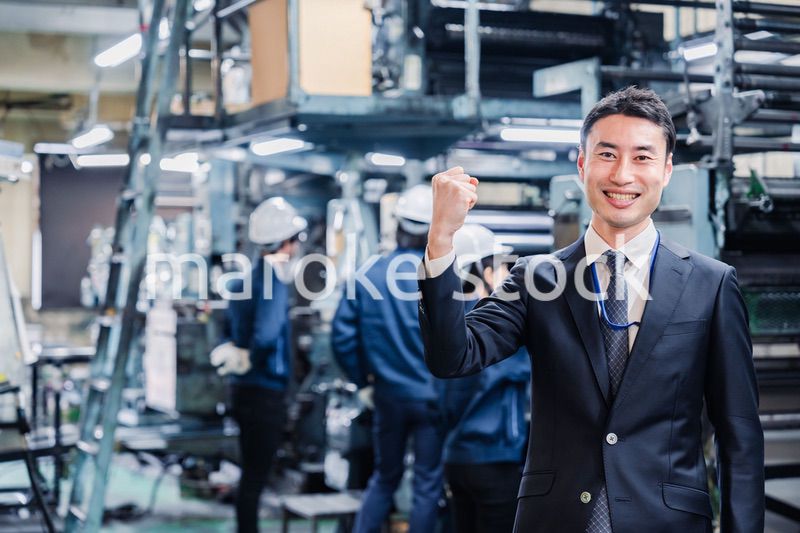 工場でガッツポーズをするビジネスマン