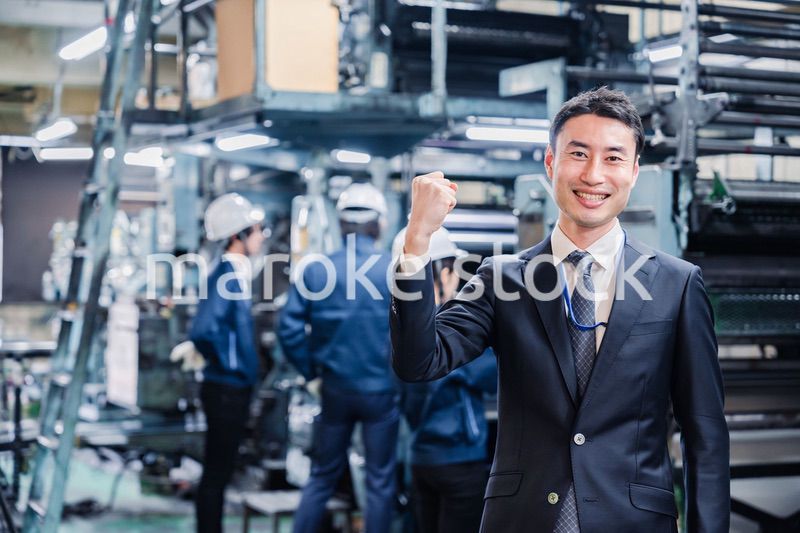 工場でガッツポーズをするビジネスマン