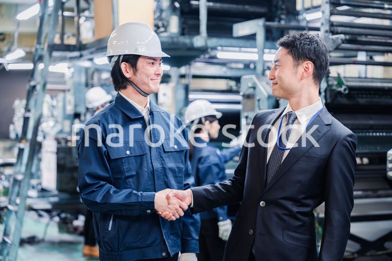 工場で握手をするビジネスマン