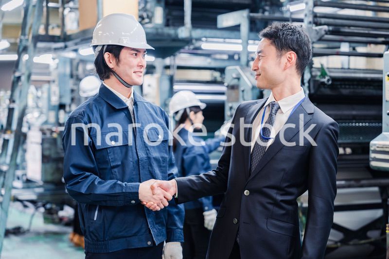 工場で握手をするビジネスマン