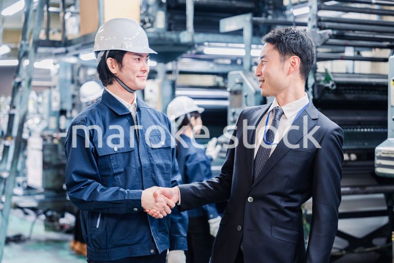 工場で握手をするビジネスマン