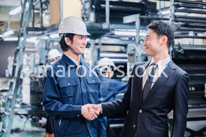 工場で握手をするビジネスマン
