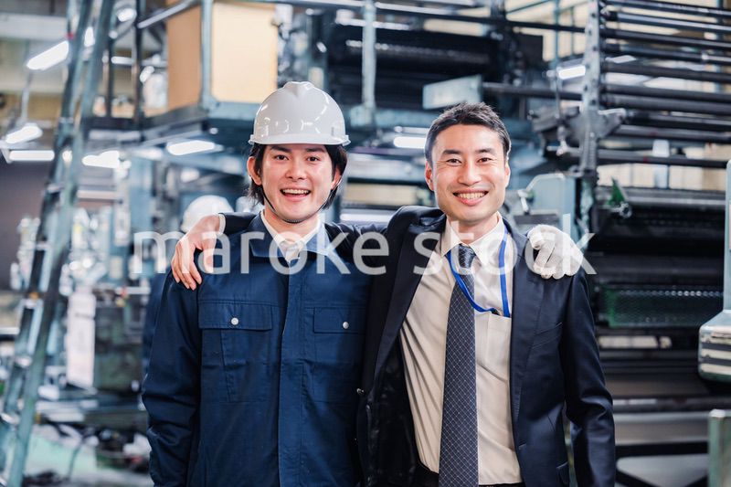 工場で肩を組む労働者と経営者