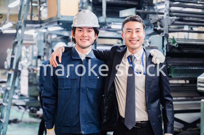 工場で肩を組む労働者と経営者