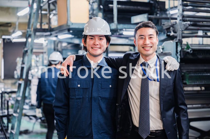 工場で肩を組む労働者と経営者