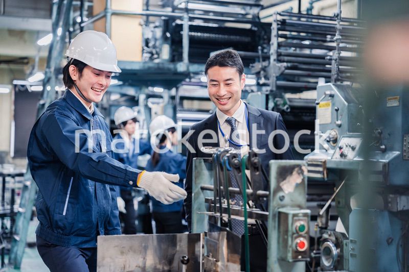 機械の前で話をする営業マンと労働者