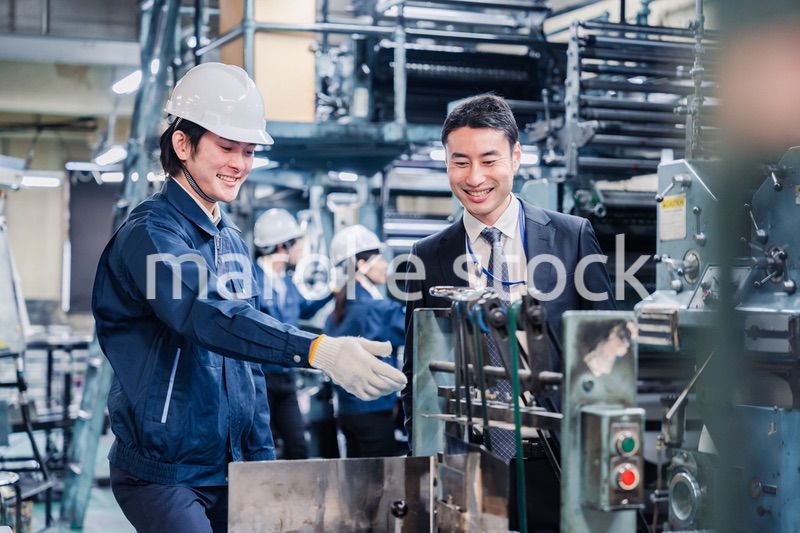 機械の前で話をする営業マンと労働者