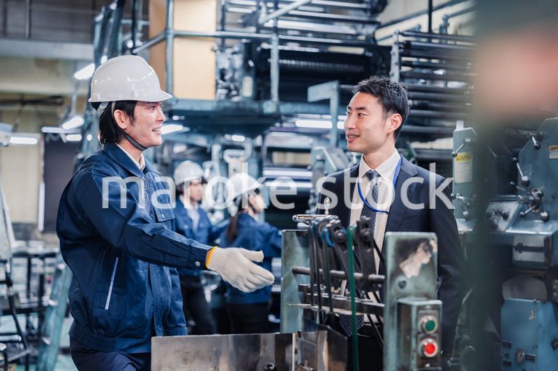 機械の前で話をする営業マンと労働者