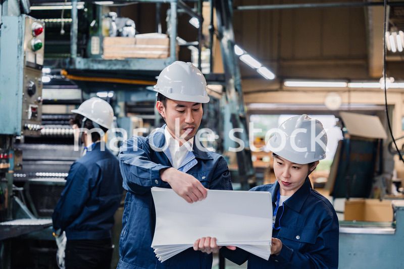 大量の紙資料を確認する工場スタッフ