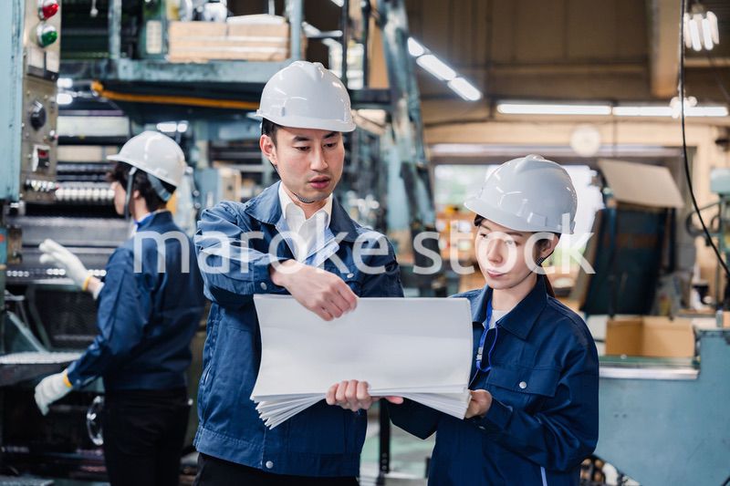 大量の紙資料を確認する工場スタッフ