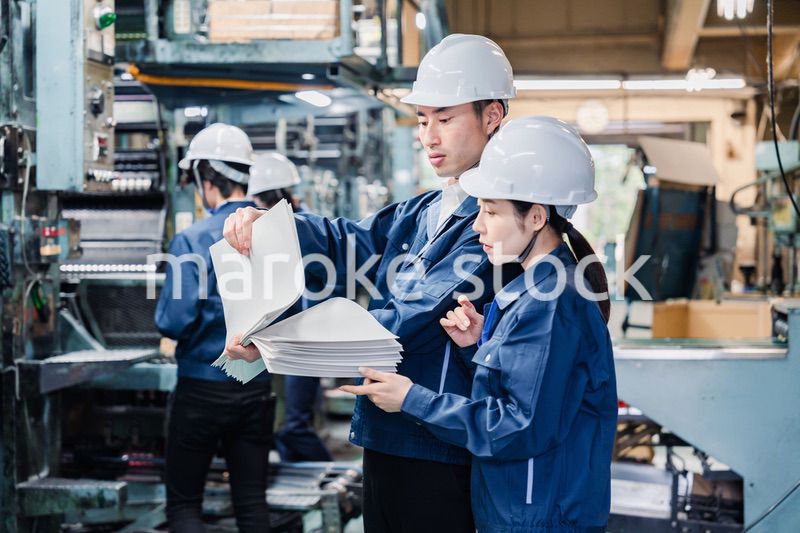 大量の紙資料を確認する工場スタッフ