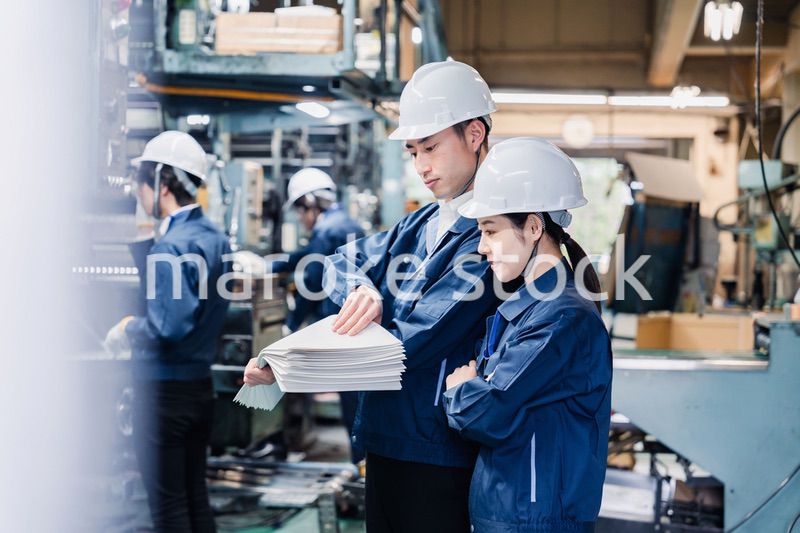 大量の紙資料を確認する工場スタッフ