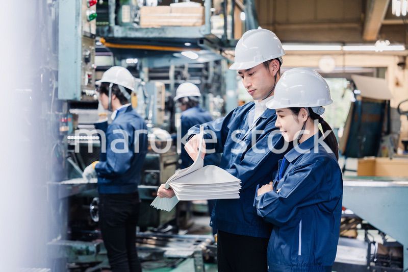 大量の紙資料を確認する工場スタッフ