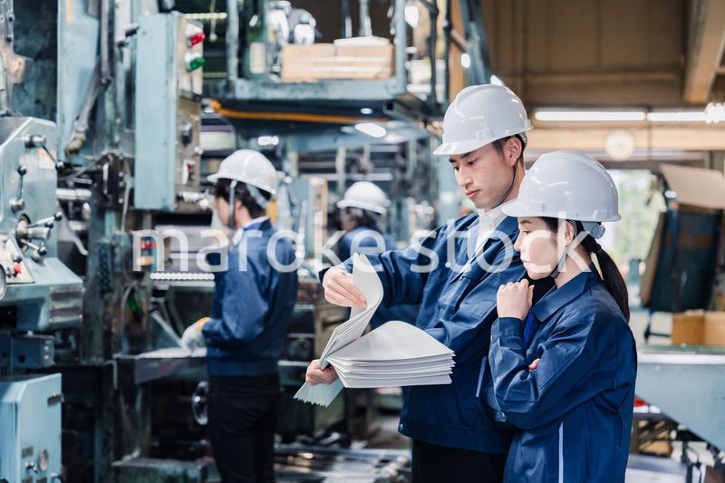 大量の紙資料を確認する工場スタッフ