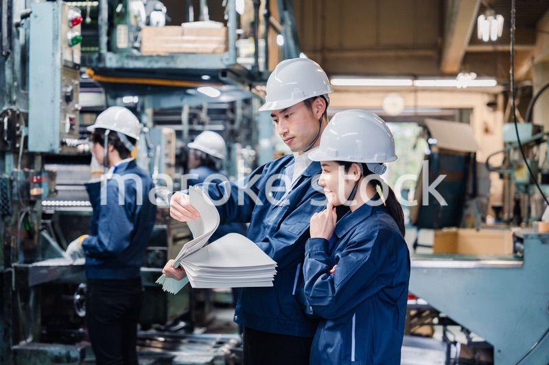 大量の紙資料を確認する工場スタッフ