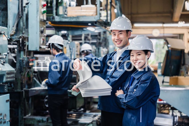 大量の紙資料を確認する工場スタッフ