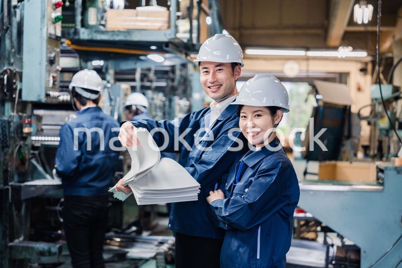 大量の紙資料を確認する工場スタッフ