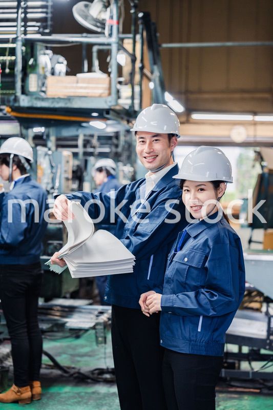 大量の紙資料を確認する工場スタッフ