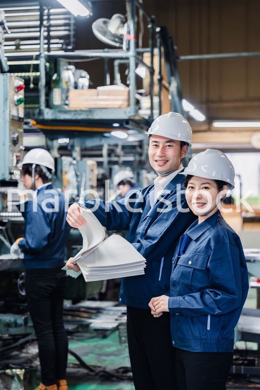 大量の紙資料を確認する工場スタッフ