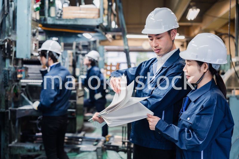大量の紙資料を確認する工場スタッフ