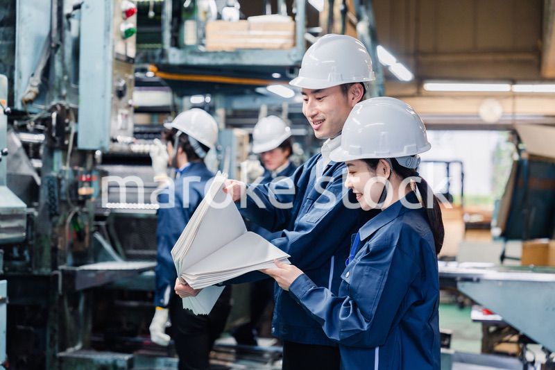 大量の紙資料を確認する工場スタッフ