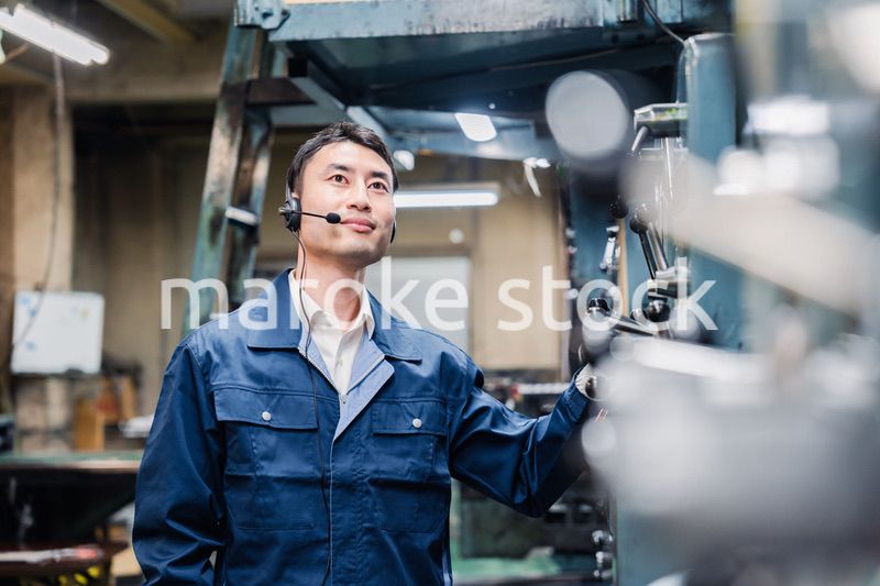 ヘッドセットをつけて重機を操作する男性作業員