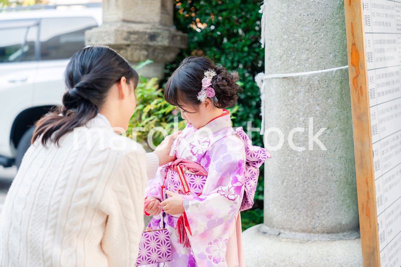 七五三をお祝いする子どもと服を整えるお母さん