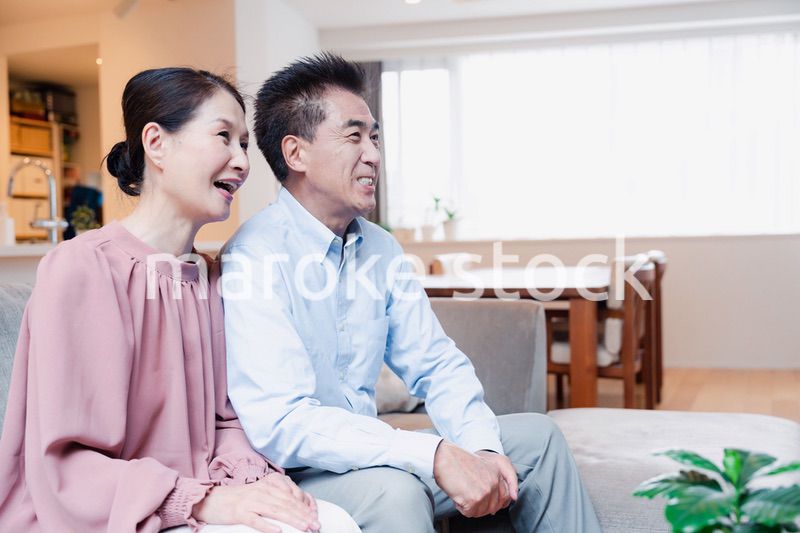 家でテレビを見るシニアの夫婦