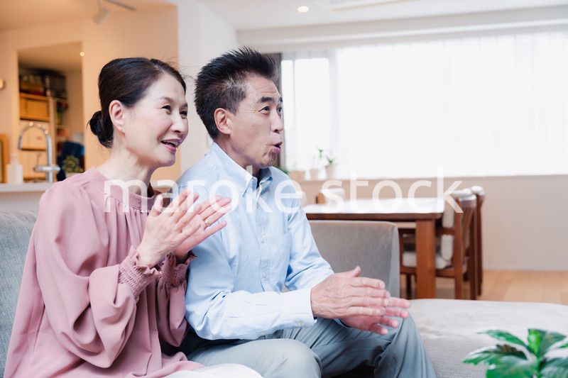 家でテレビを見るシニアの夫婦