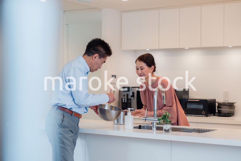 キッチンで一緒にクッキングを楽しむシニアの夫婦