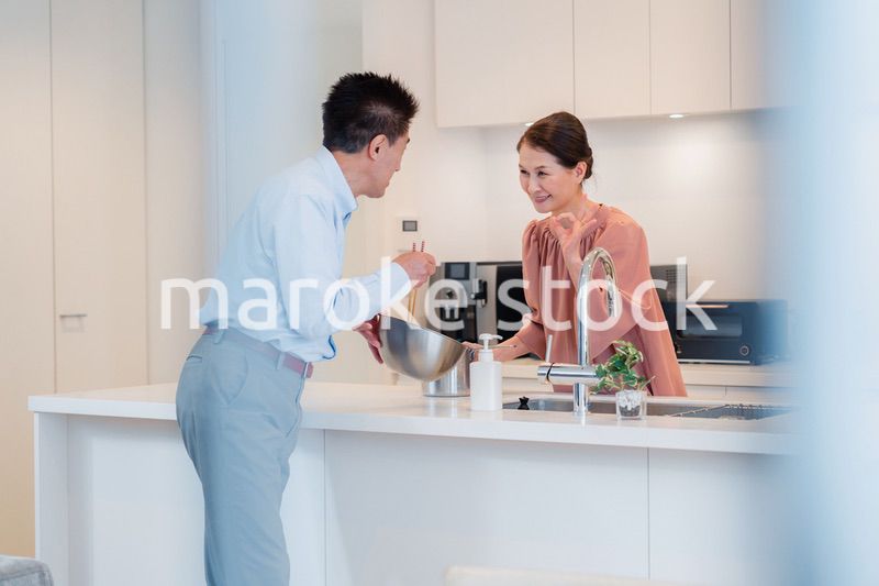 キッチンで一緒にクッキングを楽しむシニアの夫婦