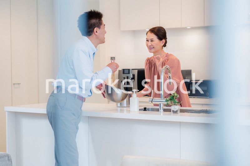 キッチンで一緒にクッキングを楽しむシニアの夫婦