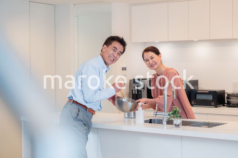 キッチンで一緒にクッキングを楽しむシニアの夫婦