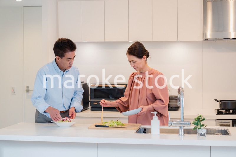 キッチンで一緒にクッキングを楽しむシニアの夫婦