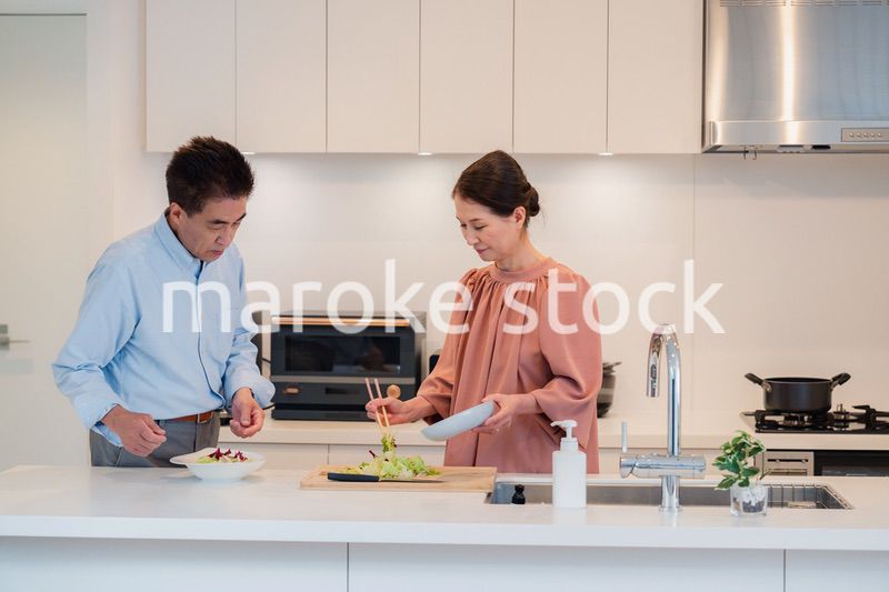 キッチンで一緒にクッキングを楽しむシニアの夫婦