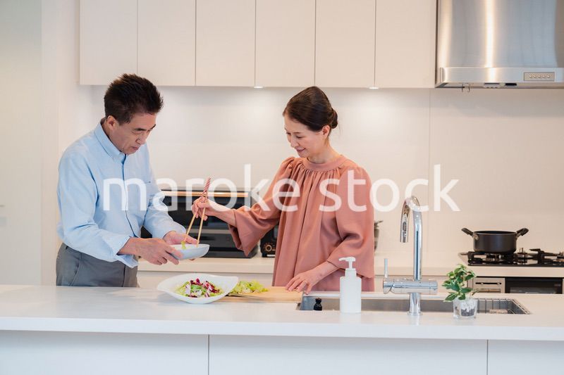キッチンで一緒にクッキングを楽しむシニアの夫婦