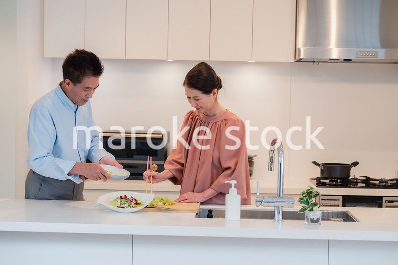 キッチンで一緒にクッキングを楽しむシニアの夫婦