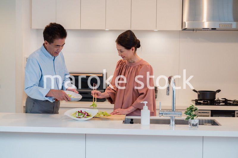 キッチンで一緒にクッキングを楽しむシニアの夫婦