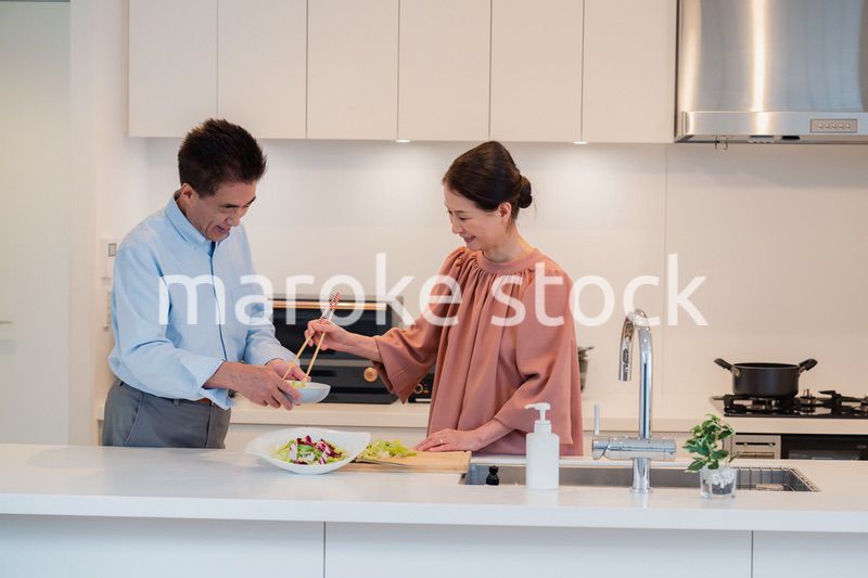キッチンで一緒にクッキングを楽しむシニアの夫婦