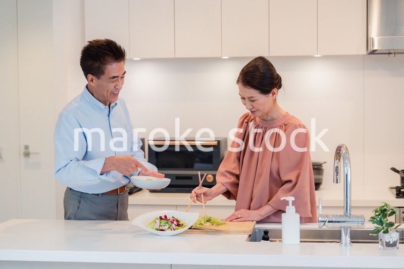キッチンで一緒にクッキングを楽しむシニアの夫婦
