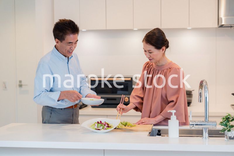 キッチンで一緒にクッキングを楽しむシニアの夫婦